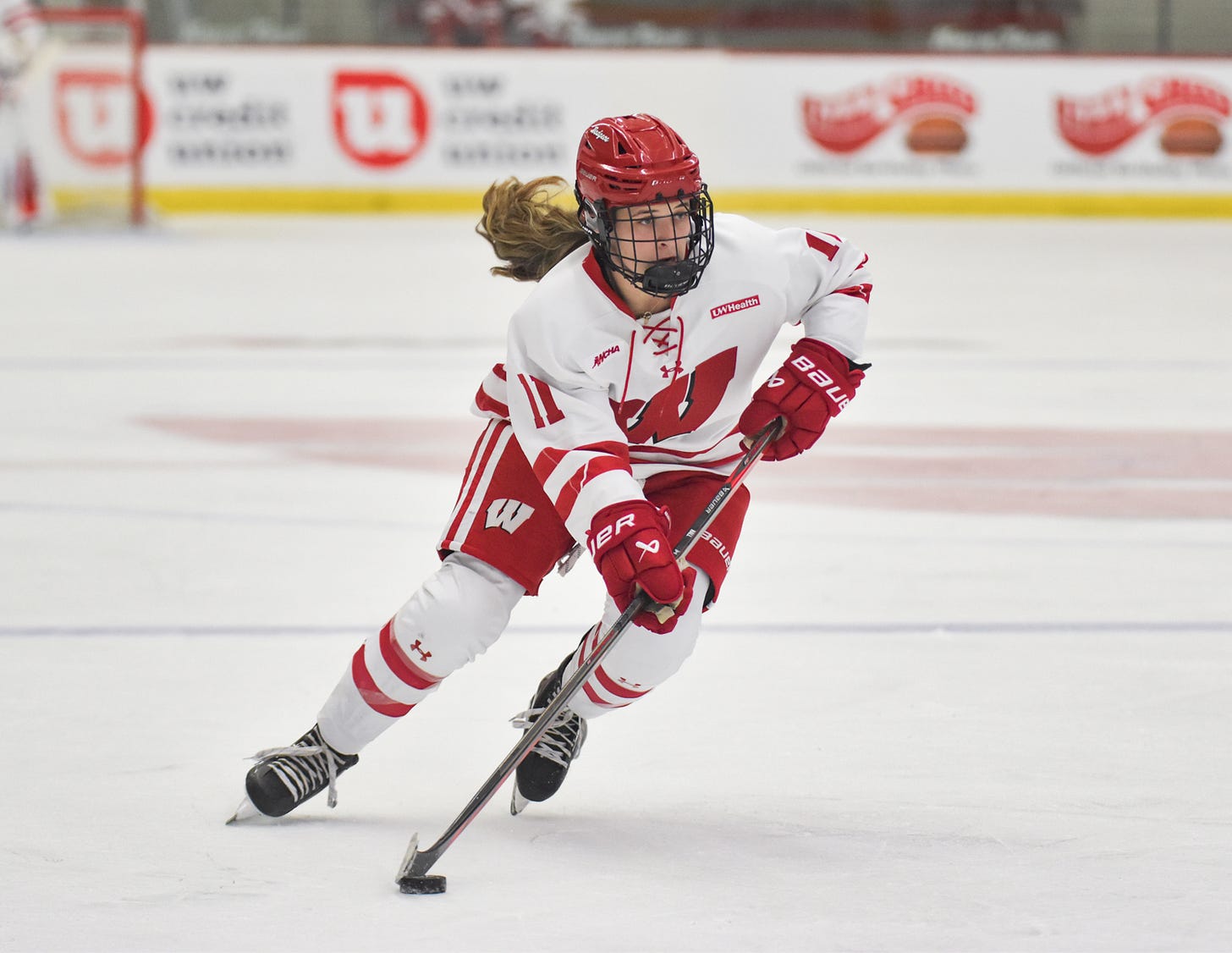 Wisconsin women's hockey center Cassie Hall skates into the offensive zone with the puck on her stick