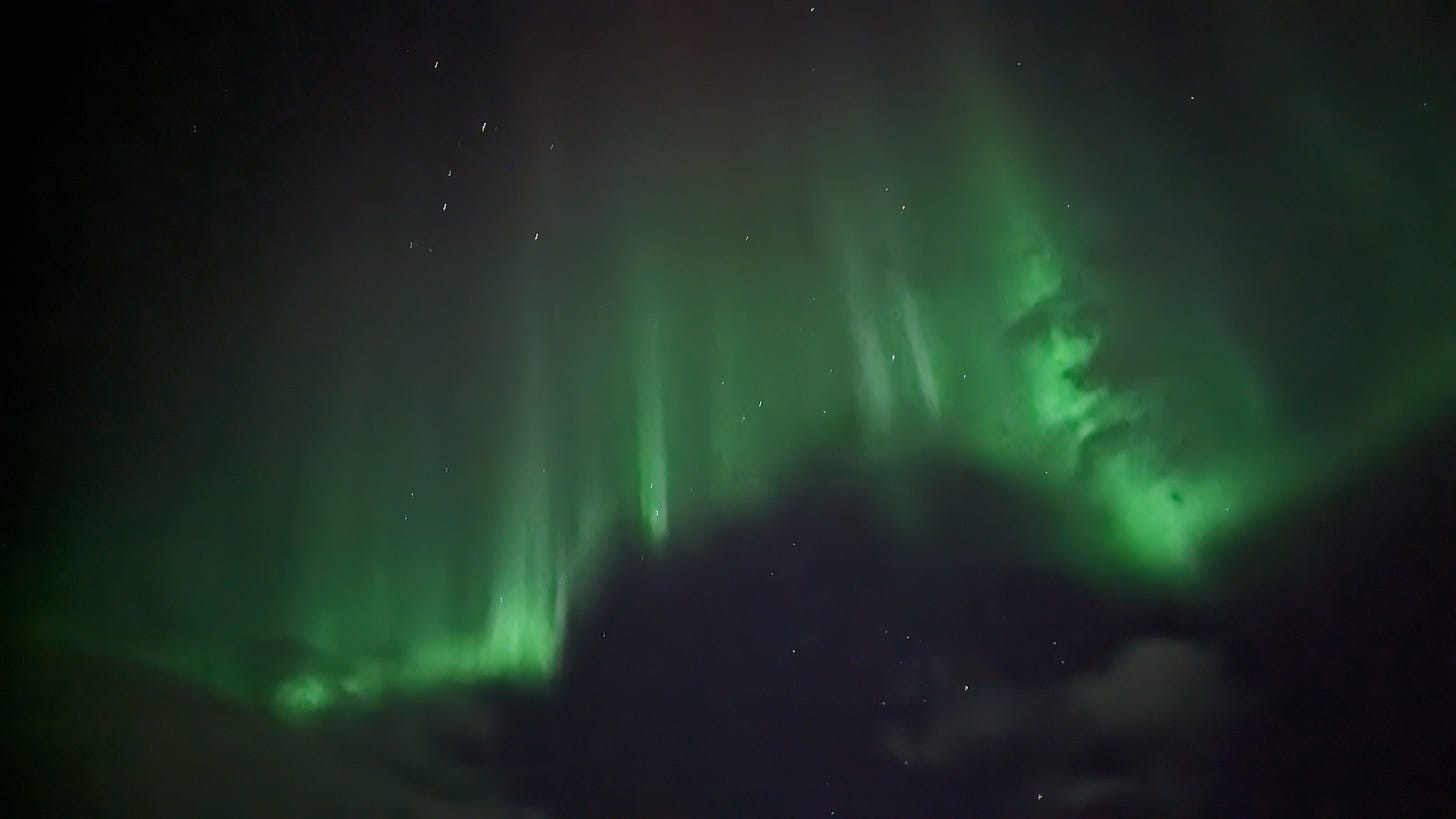 Shifting green curtains with shadows that look remarkably like a face in the sky