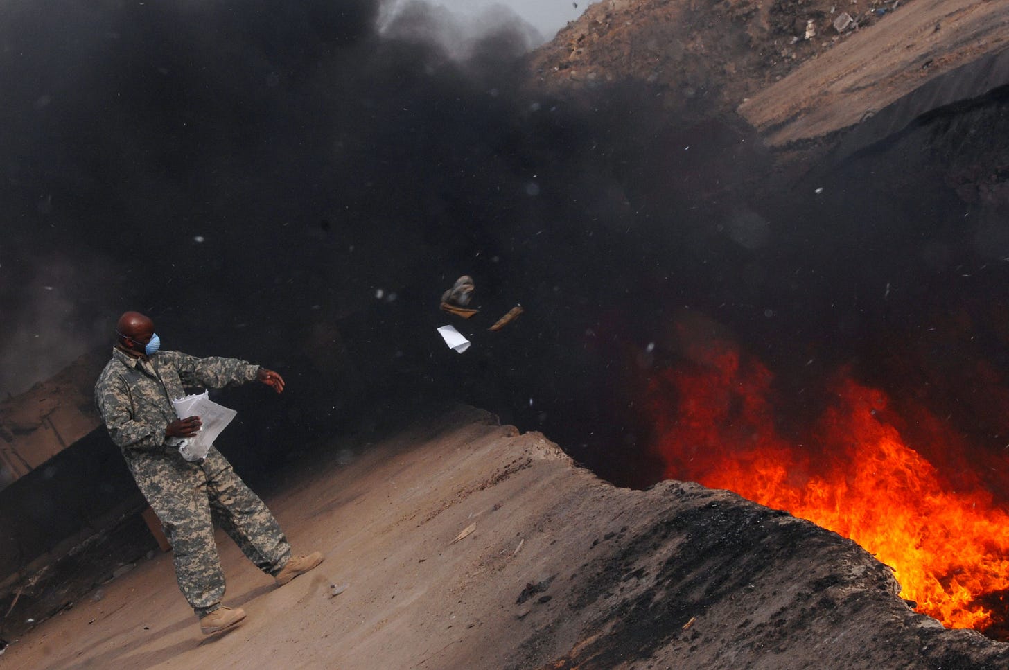 Master Sgt. Darryl Sterling, 332nd Expeditionary Logistics Readiness Squadron equipment manager, tosses unserviceable uniform items into a burn pit, March 10. The 332 ELRS has a central collection point that can be used by service members and Department of Defense civilians; unserviceable uniform items are burned. Sgt. Sterling is deployed from Luke Air Force Base, Ariz. (U.S. Air Force photo/Senior Airman Julianne Showalter)