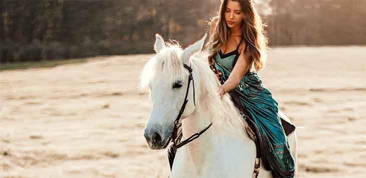 Photo of a woman sitting on a white horse.