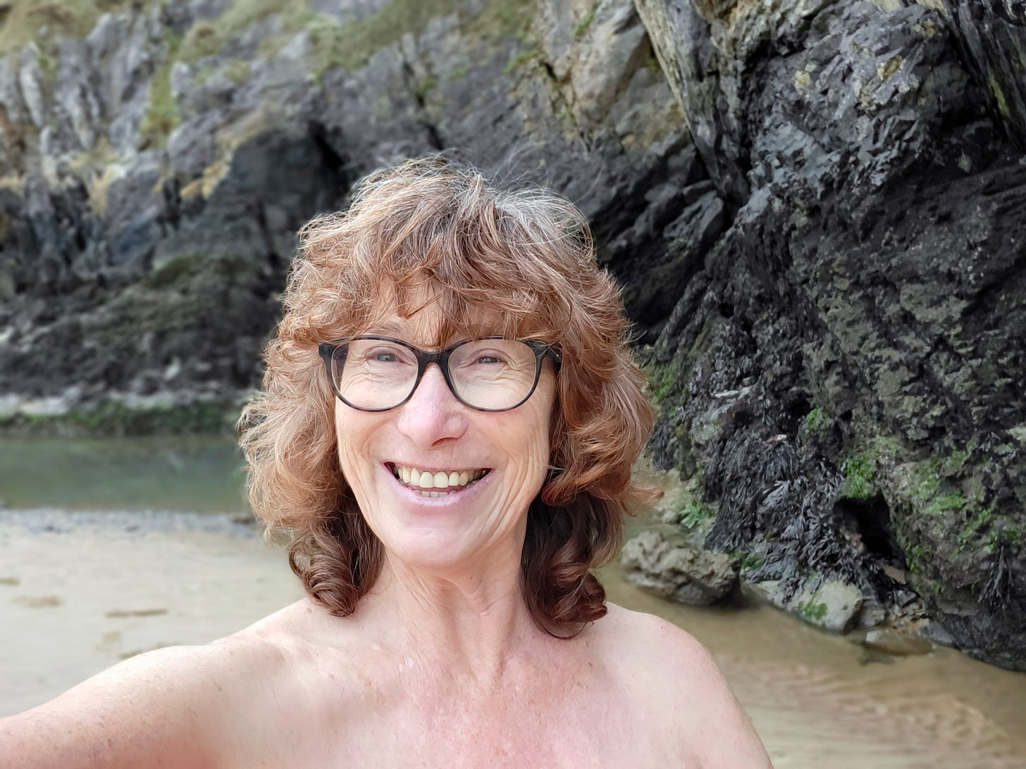 Mature woman takes a selfie while cold water skinny dipping at Three Cliffs Bay.  Mature woman takes a selfie while cold water skinny dipping at Three Cliffs Bay.