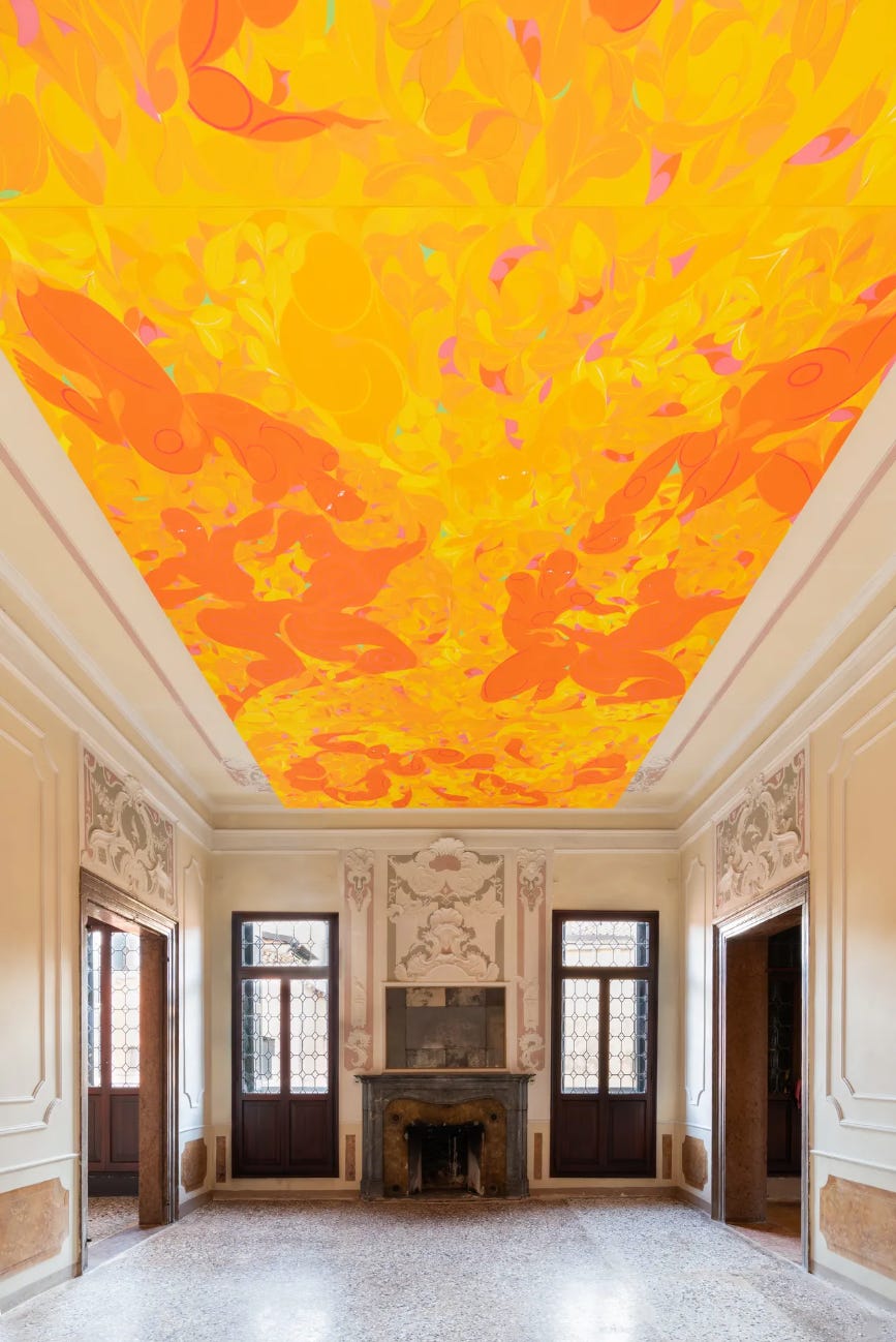 An ornate eighteenth century room with stone floor and ornate white walls and door surrounds, with a brightly painted orange and yellow artwork filling the ceiling — a product of the artist Tunji Adeniyi-Jones’ piece at Palazzo Canal at the Venice Biennale.