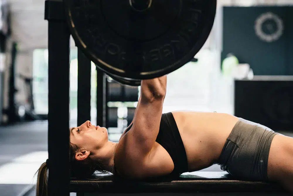 Strong woman doing barbell bench press.