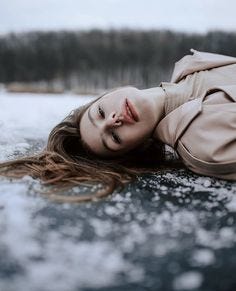 This may contain: a woman laying on the ice with her eyes closed