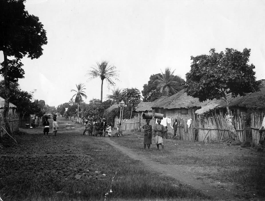 A street lined by trees and thatched-roof houses A street lined by trees and thatched-roof houses