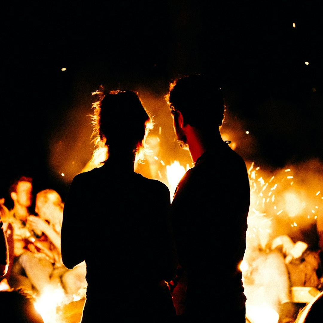 two persons standing in front of bonfire two persons standing in front of bonfire