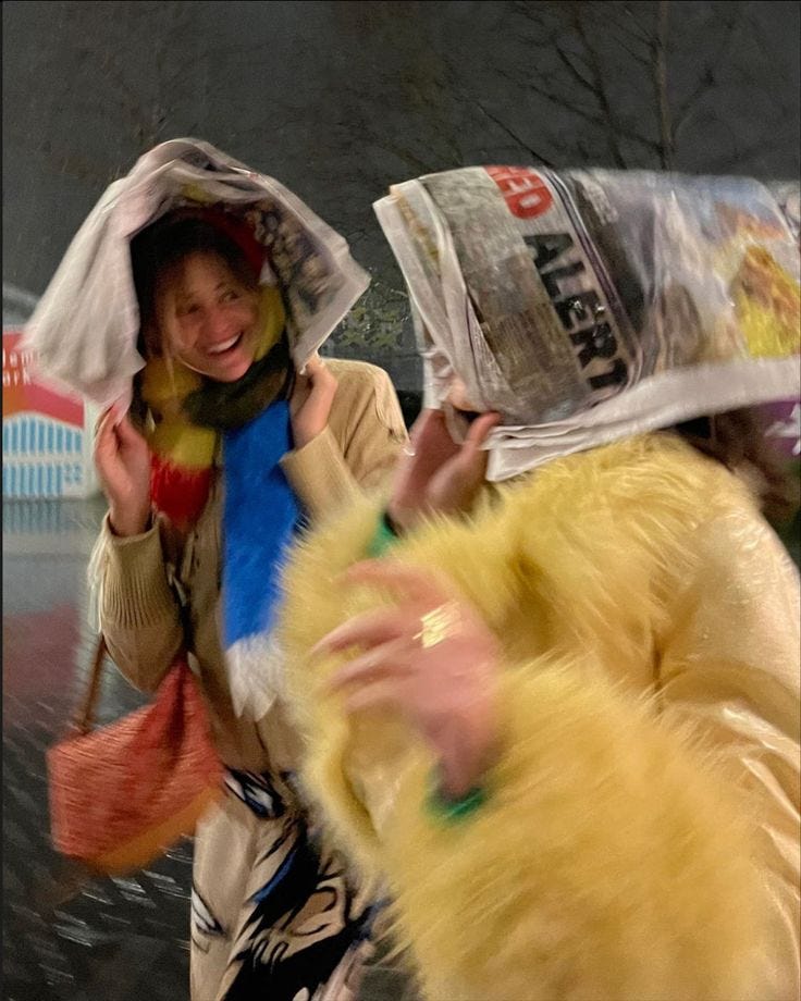 This may contain: two women walking down the street with bags on their heads