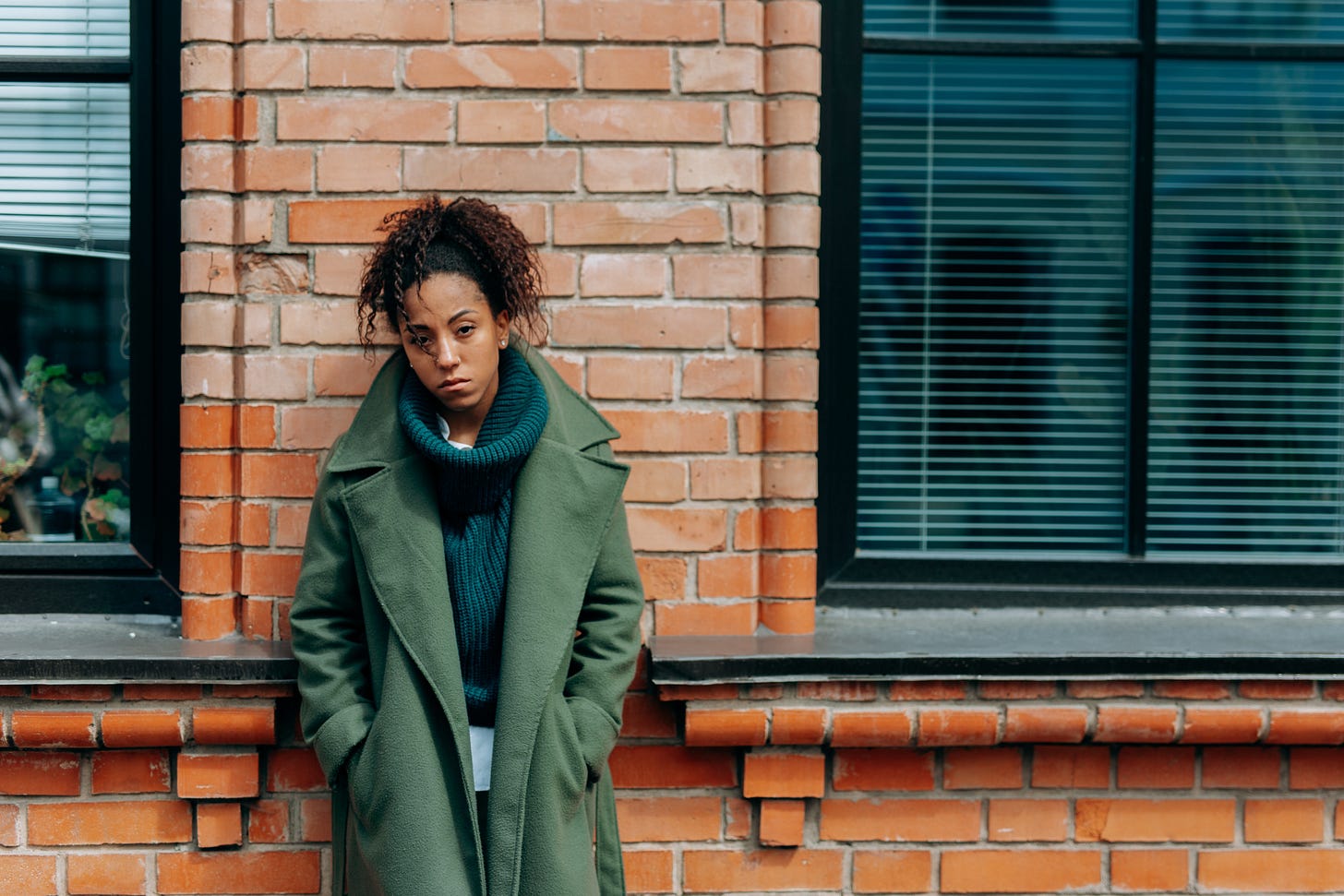A Lonely Woman Leaning on a Brick Wall