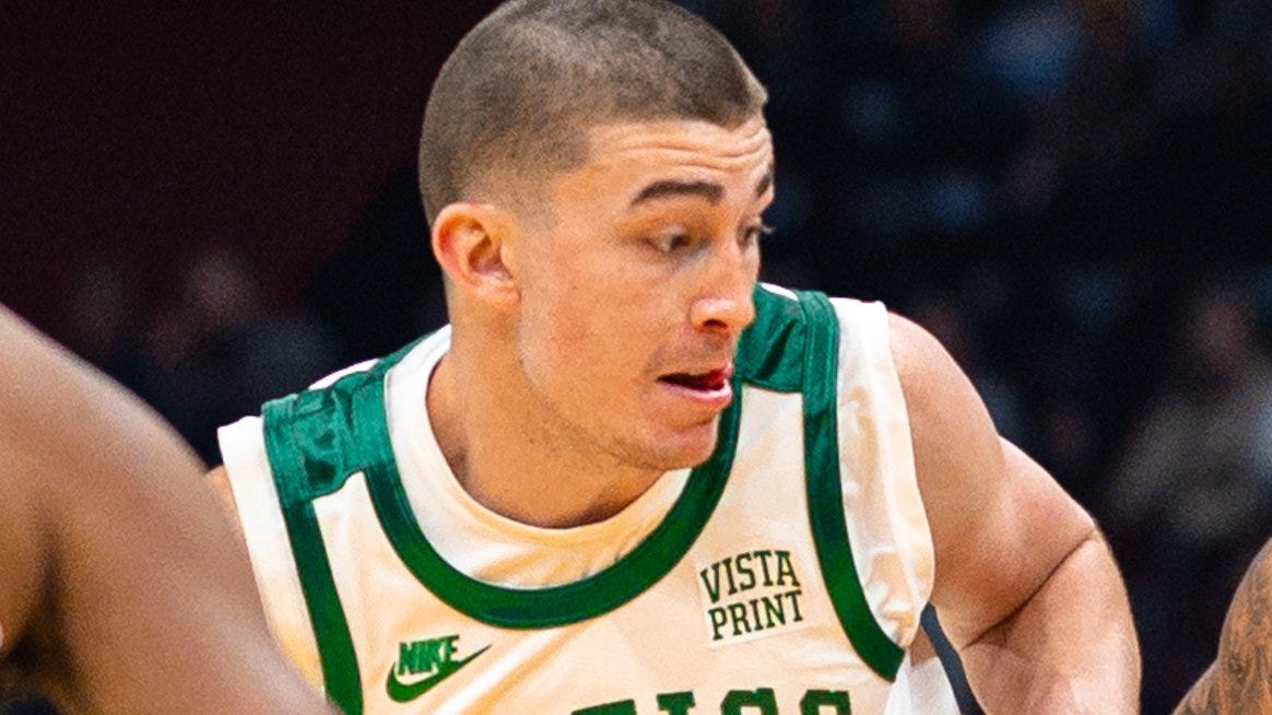 Celtics guard in a cream and green jersey dribbling past a defender. Celtics guard in a cream and green jersey dribbling past a defender.