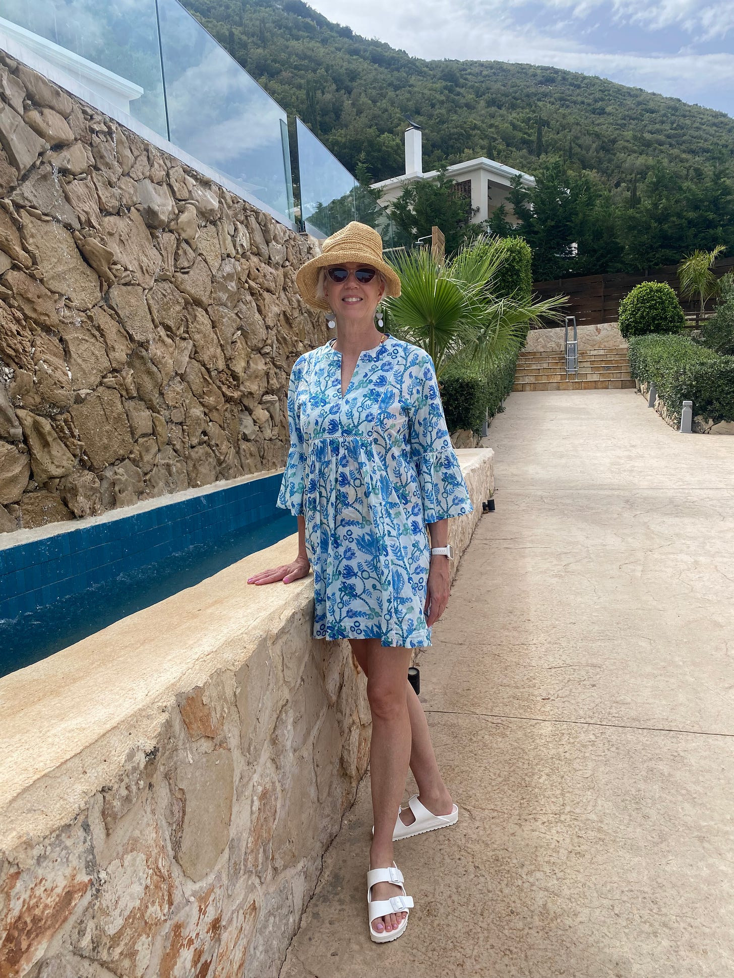 Woman standing by a wall outside of a Greek villa in Greece