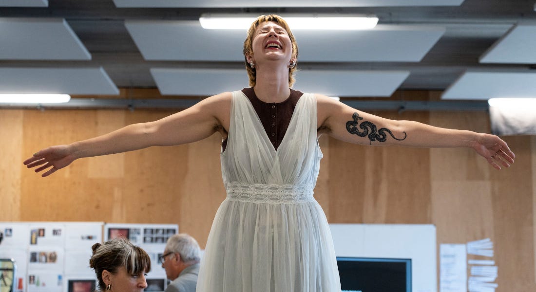 A woman with short hair, wearing a wedding dress, holds her arms out wide, throws her head back and is smiling widely. A woman with short hair, wearing a wedding dress, holds her arms out wide, throws her head back and is smiling widely.