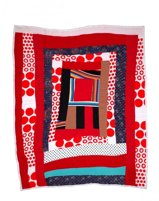 A quilt made by a Gee's bend quilter with red and blue strips of fabric formed into a log cabin pattern