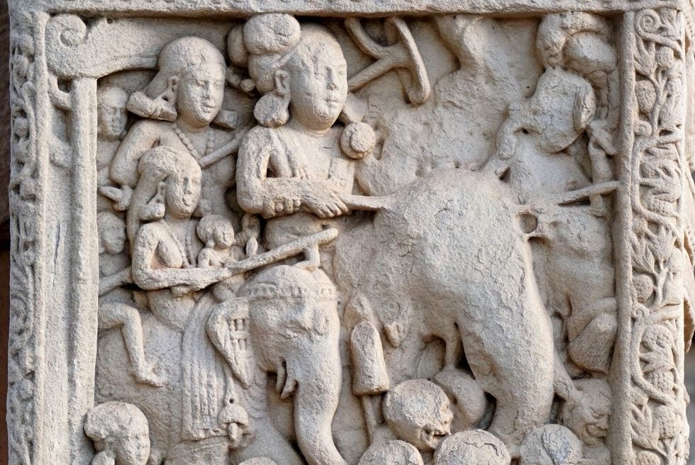 a stone relief shows a person riding on a elephant as several other people ride and walk near him