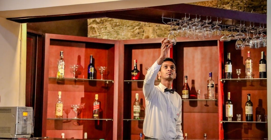 a man standing in front of a bar with many bottles of alcohol