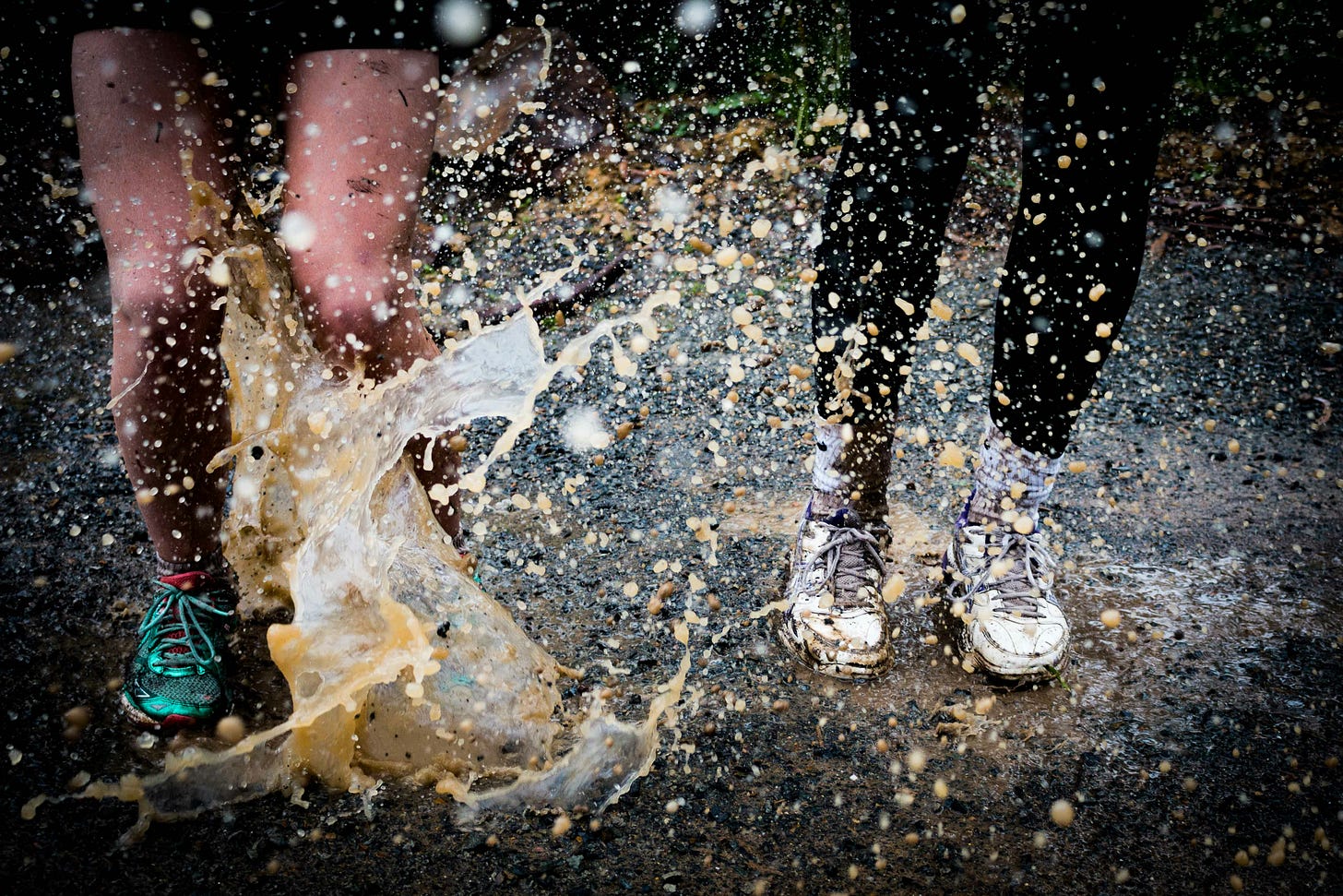 Two children's feet/legs splashing messily in a puddle Two children's feet/legs splashing messily in a puddle