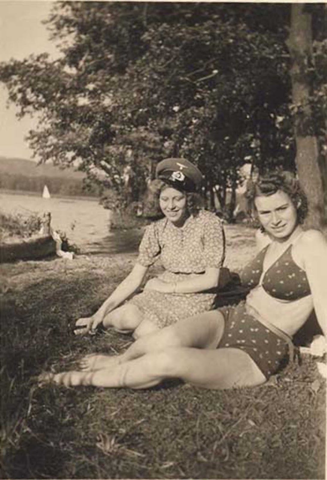 French women, one conspicuously wearing a German hat, indicating a connection to the occupying forces. French women, one conspicuously wearing a German hat, indicating a connection to the occupying forces.