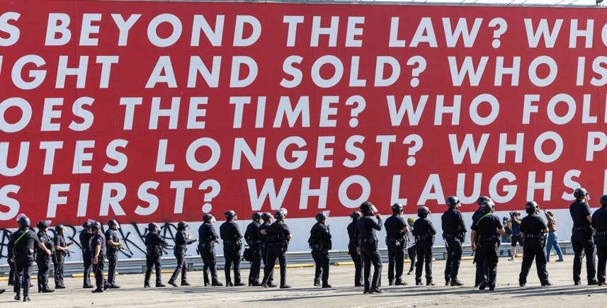 Police officers stand in line, as protesters clash with law enforcement in the streets surrounding the federal building during a protest following federal immigration operations in Los Angeles, on June 8, 2025.