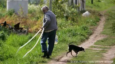 Jose Mujica pulls a hose as he walks down a sandy track on his farm with his dog in october 2009. Jose Mujica pulls a hose as he walks down a sandy track on his farm with his dog in october 2009.