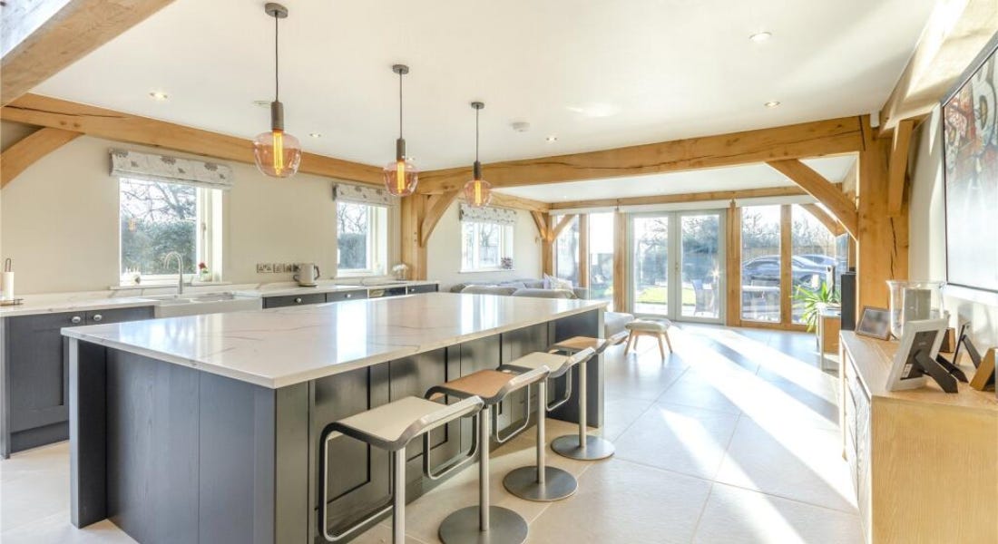 A kitchen with wooden beams, white walls and ceilings, a kitchen island, and stools A kitchen with wooden beams, white walls and ceilings, a kitchen island, and stools