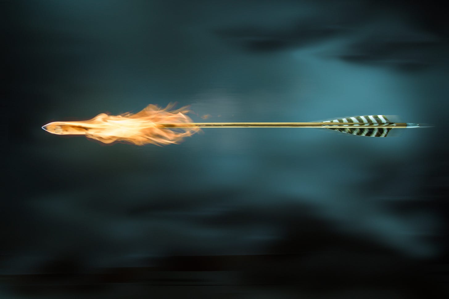 Picture of arrow with a flaming head against a dark clouded sky