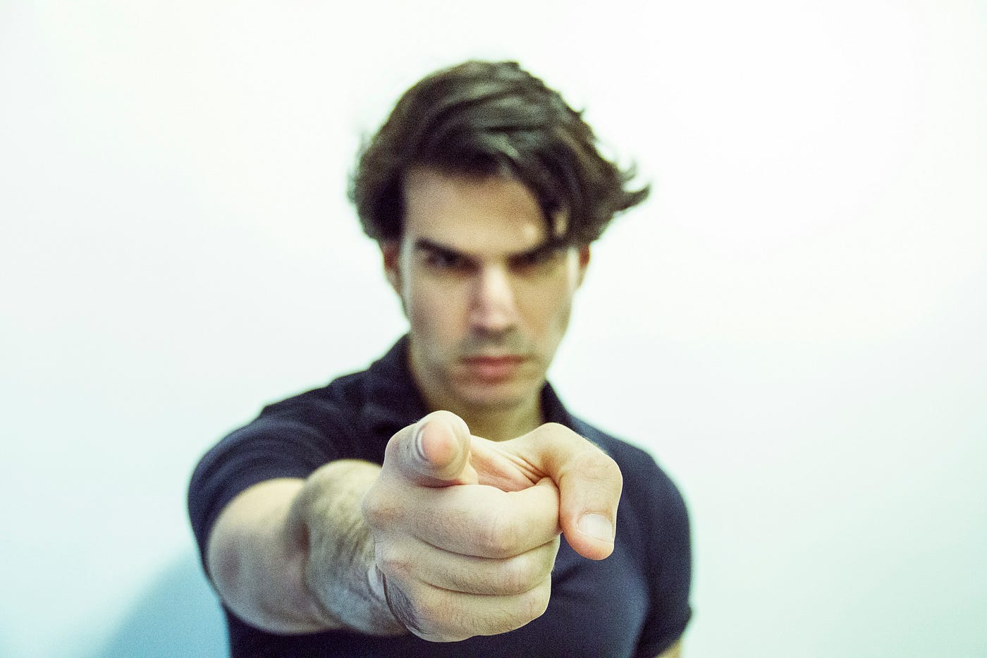 A young man looks angry and points a finger at the viewer