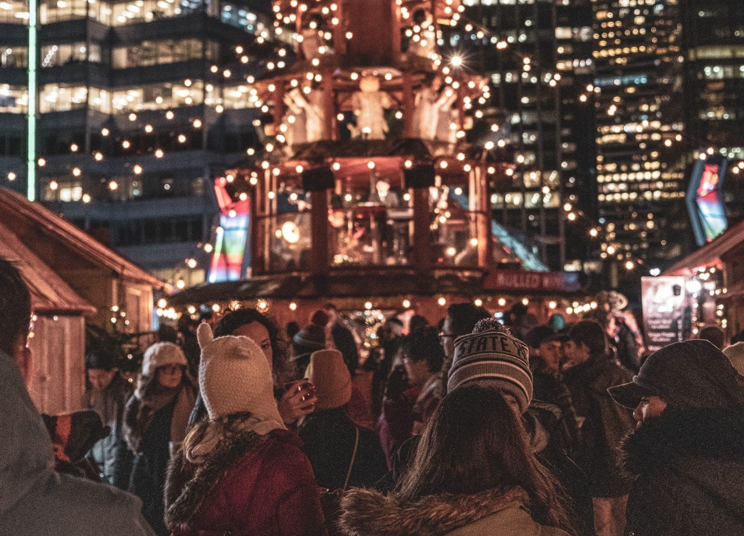 Crowded holiday market at night with festive lights and winter crowding