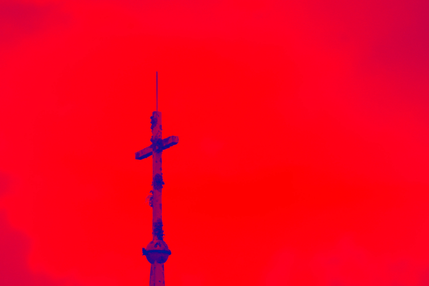 A cross silhouette against a red background. 