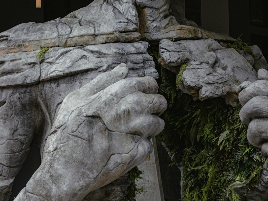 gray concrete statue of man holding stick