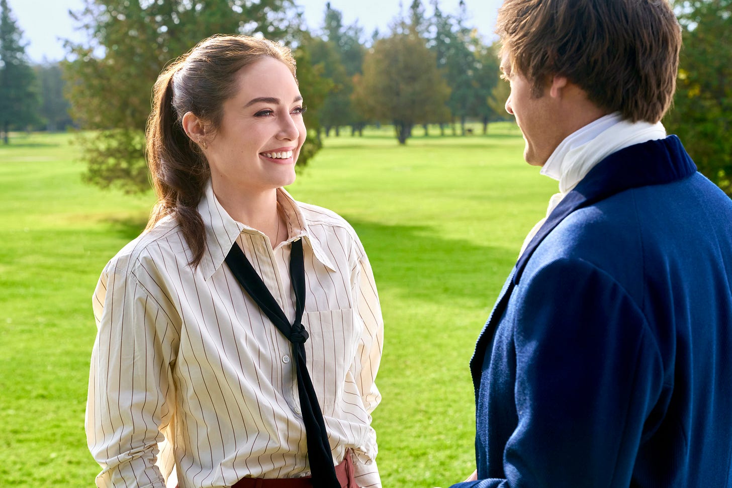 A pretty woman in modern dress smiles at a man in costume. A pretty woman in modern dress smiles at a man in costume.