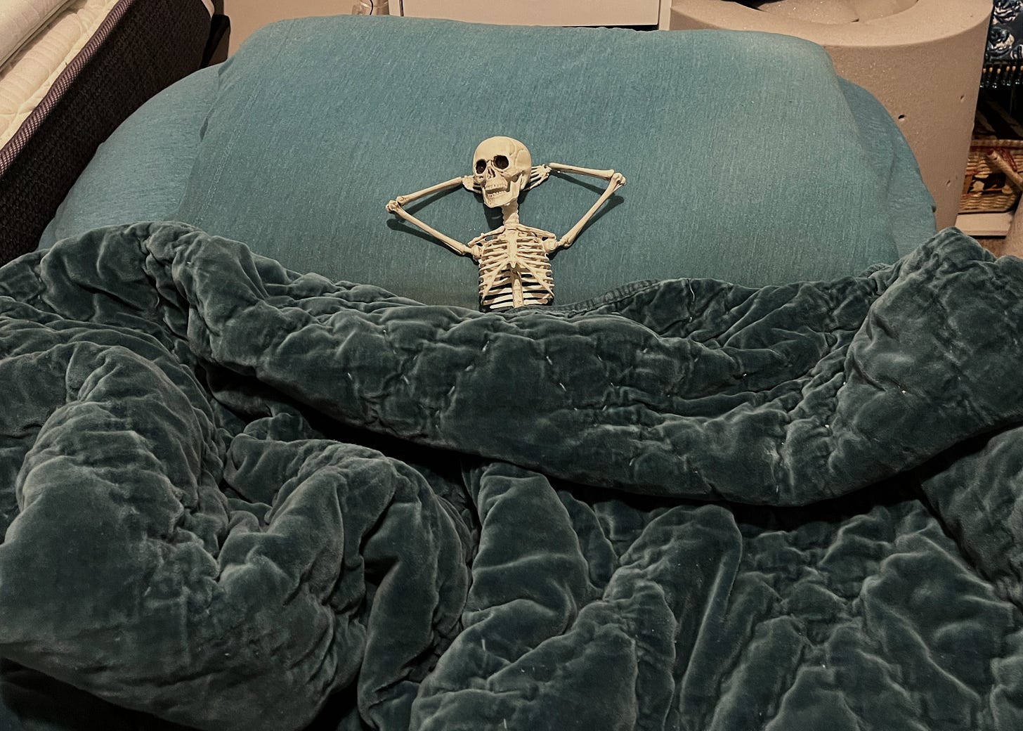 A toy skeleton lying down on a bed.