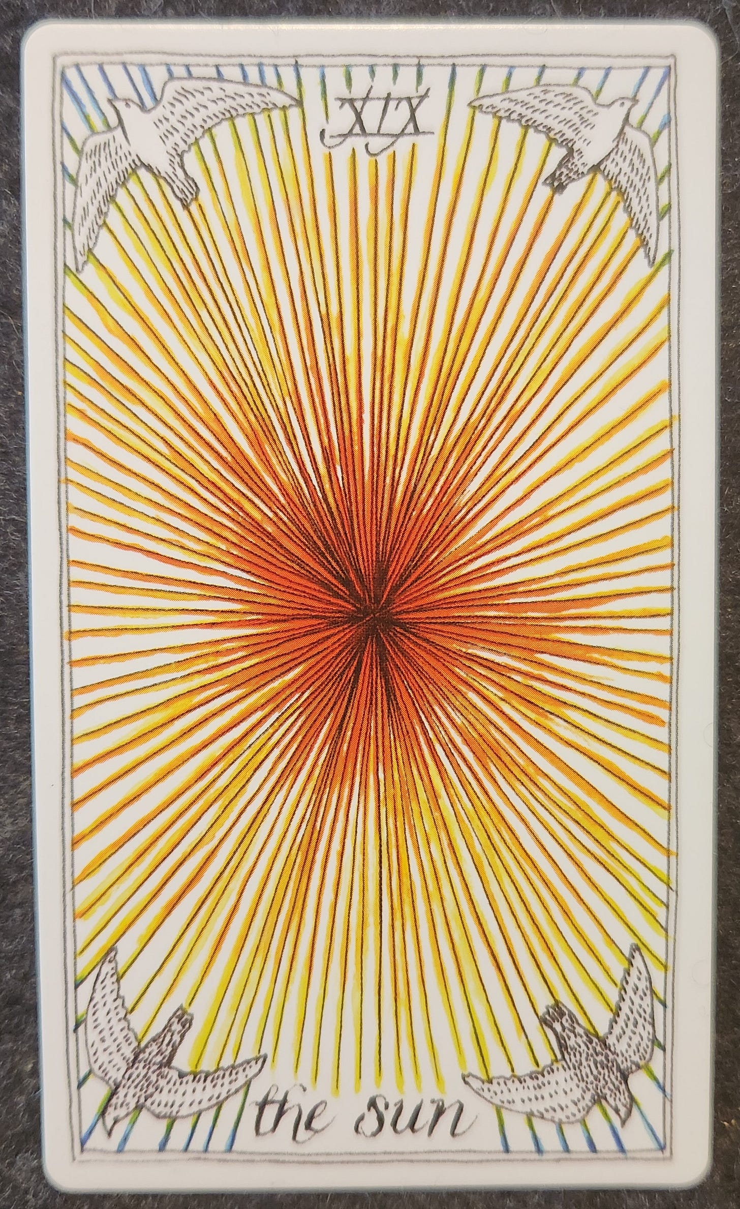 A tarot card labelled XIX the sun. A brightly shining sun fills the card. Each corner contains a bird with an open wingspan, facing towards the shining sun. 