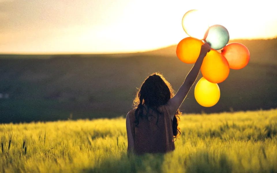 Femme dans un champ tenant des ballons Femme dans un champ tenant des ballons