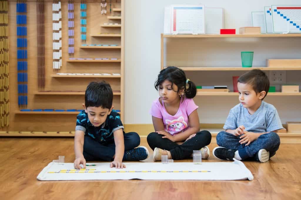 Young children engaging in hands-on learning activity in a Montessori classroom.