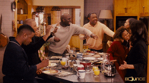 One person sits at the kitchen table calmly eating breakfast while total chaos erupts around them—everyone else in the room is yelling, fighting, and gesturing wildly.