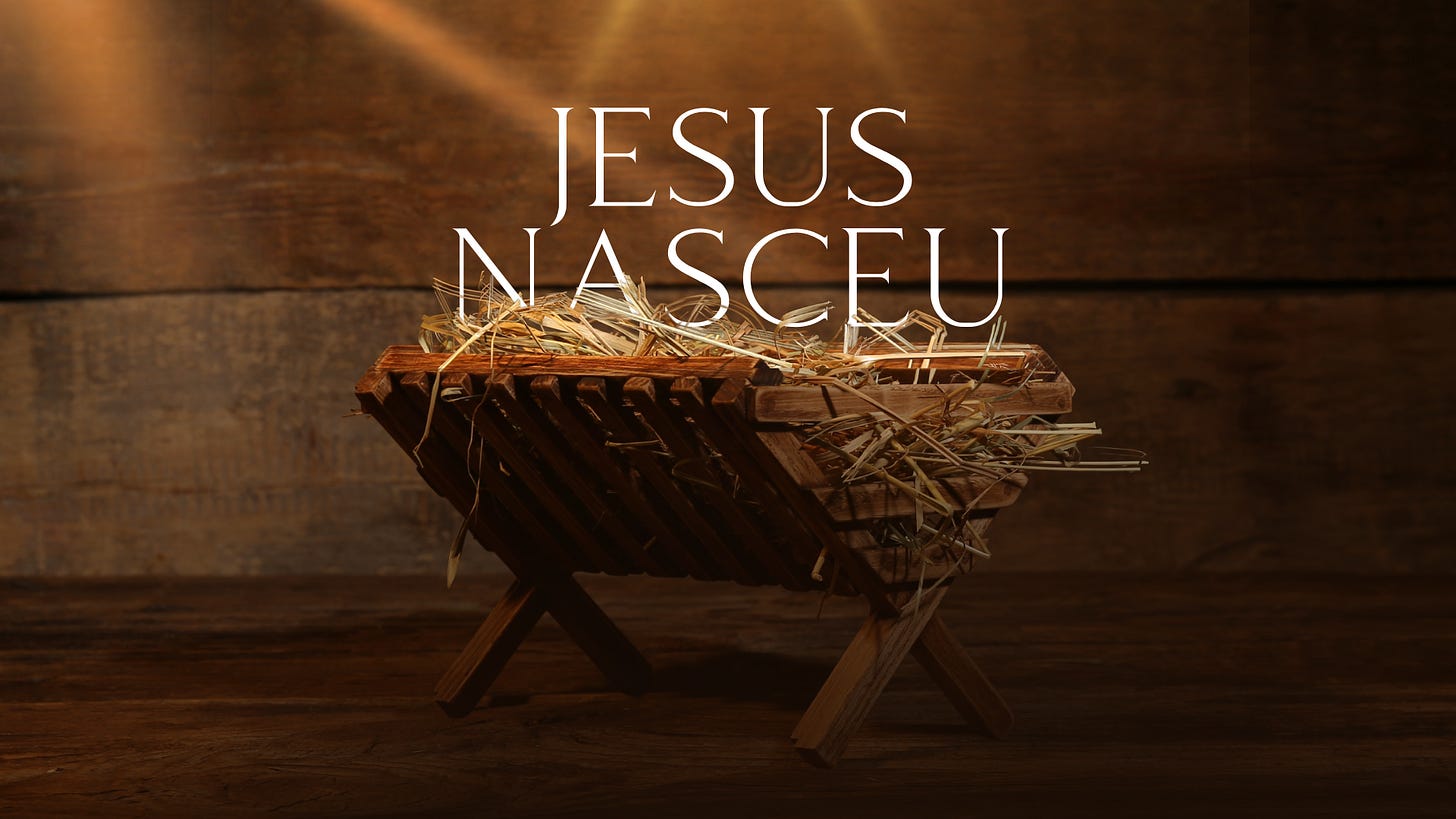 Uma foto mostrando em aposento de madeira com uma manjedoura no centro, com as palavra "Jesus Nasceu" acima dela.