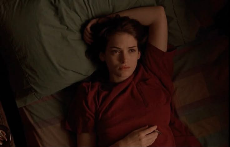 This may contain: a woman laying in bed with her hand on her head