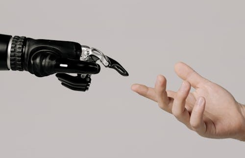 Free A human hand reaching to touch a bionic prosthetic hand on a white background. Stock Photo