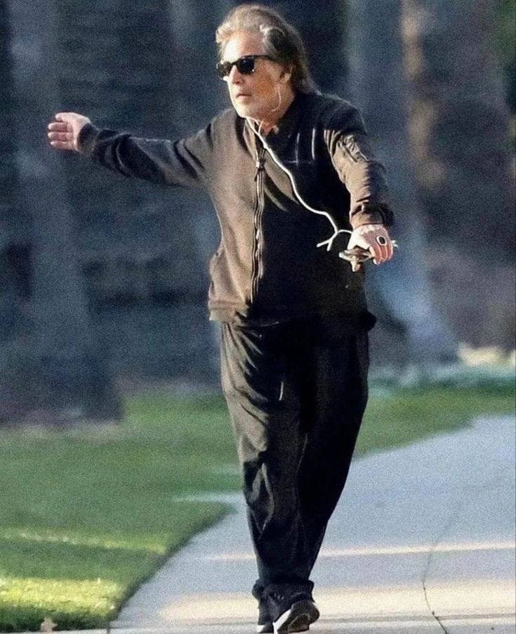 This may contain: the man is walking down the sidewalk with headphones on