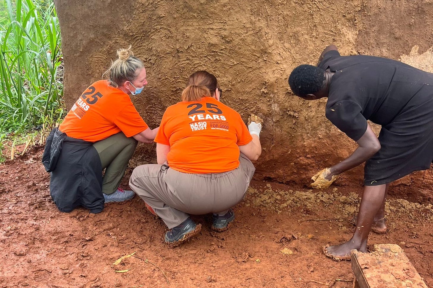Volunteers help a local woman smear mud on a house in Kenya