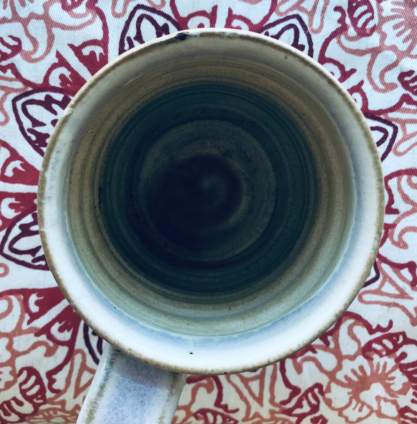 an empty ceramic mug sits on top of a cloth napkin with a floral design