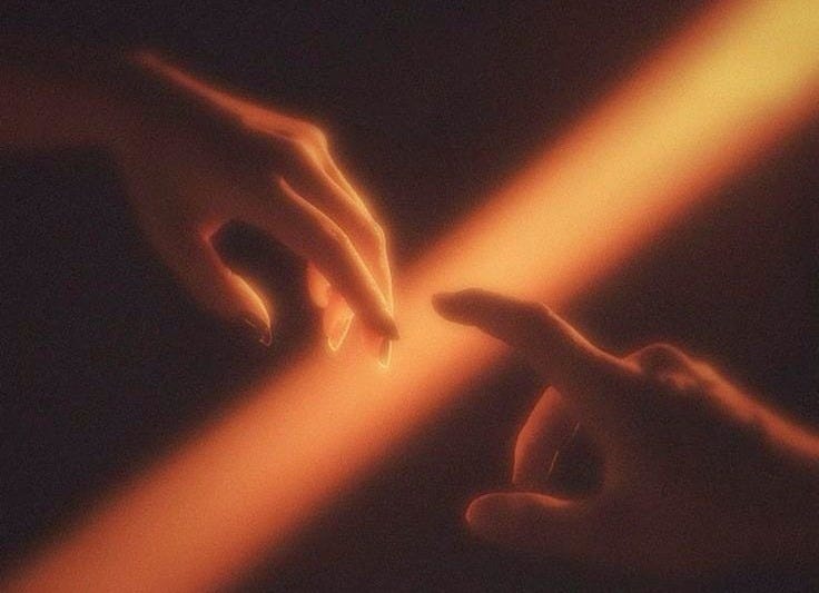 This may contain: two hands reaching towards each other with light coming from them in the dark night sky