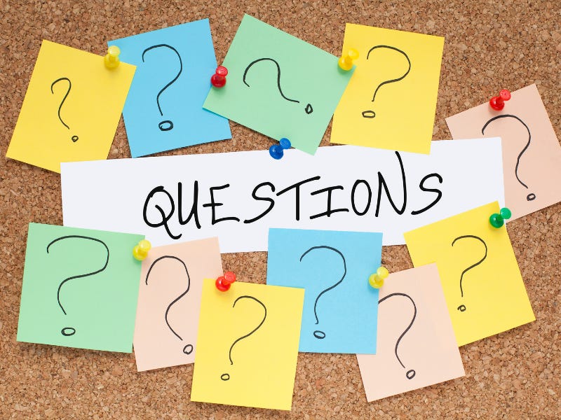 A bulletin board has the word "questions" on it surrounded by small sticky notes with question marks.