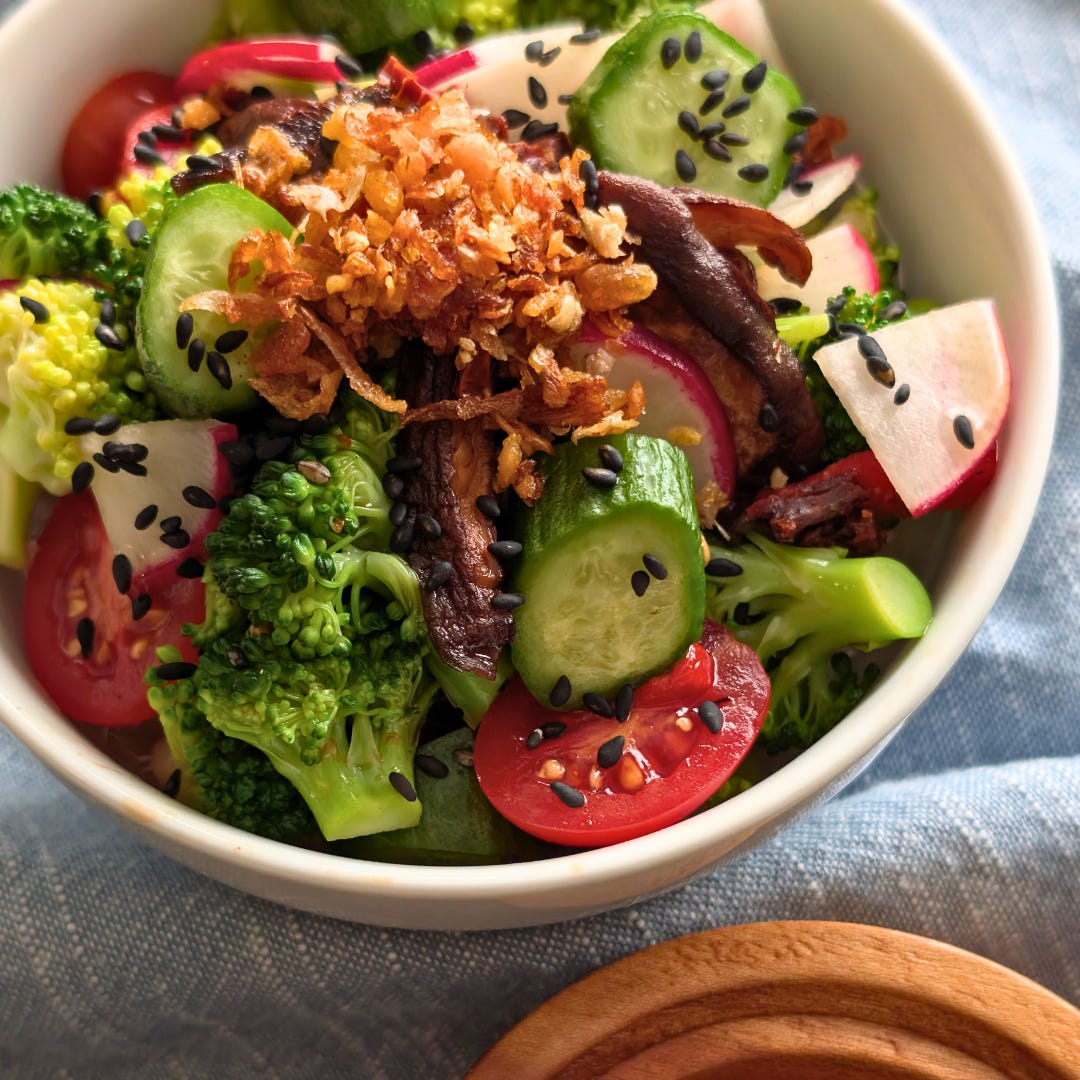 Close-up of broccoli and roasted shiitake mushroom salad, dressed in a glossy soy-balsamic vinaigrette and topped with black sesame seeds.