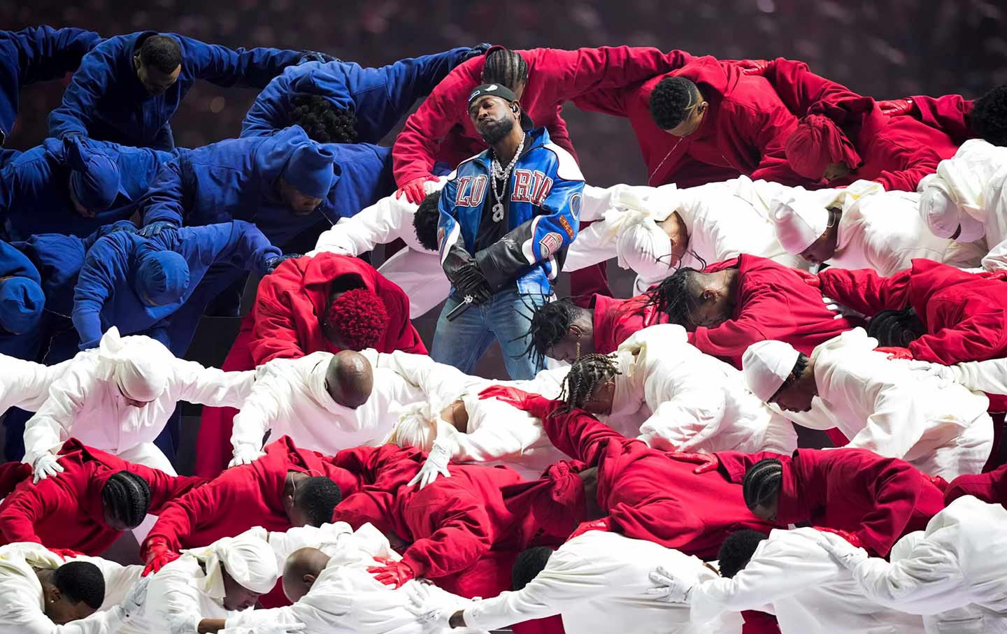 Kendrick Lamar during his performance at Super Bowl LIX surrounded by dancers wearing red, white, and blue and in the formation of an American flag.