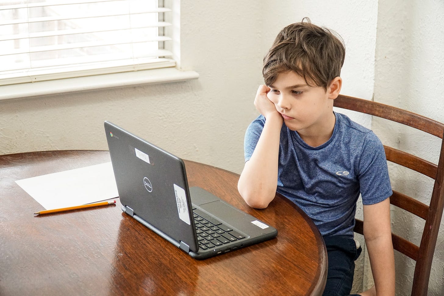 Young school aged boy looking at a laptop computer disinterested in remote learning virtual school class during COVID-19 quarantine. Young school aged boy looking at a laptop computer disinterested in remote learning virtual school class during COVID-19 quarantine.