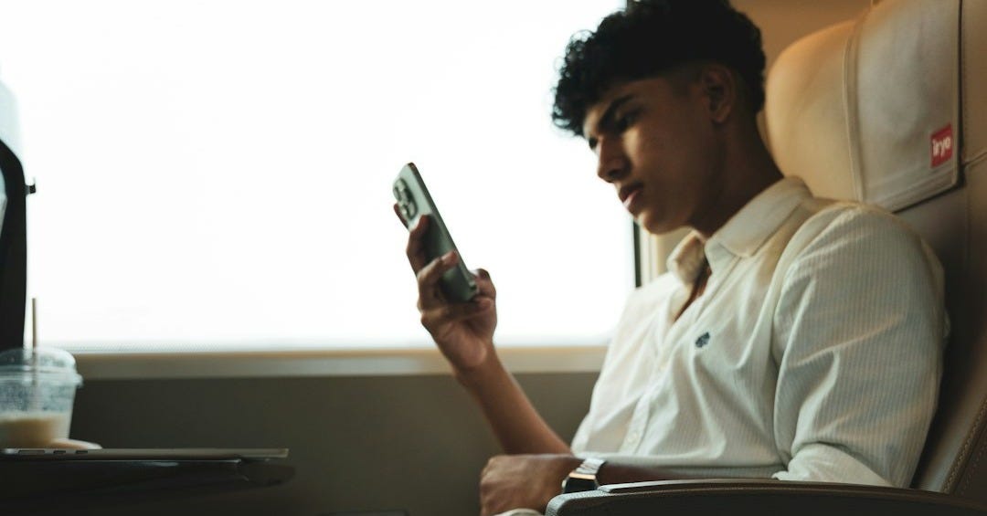 A man sitting on a train looking at his cell phone A man sitting on a train looking at his cell phone