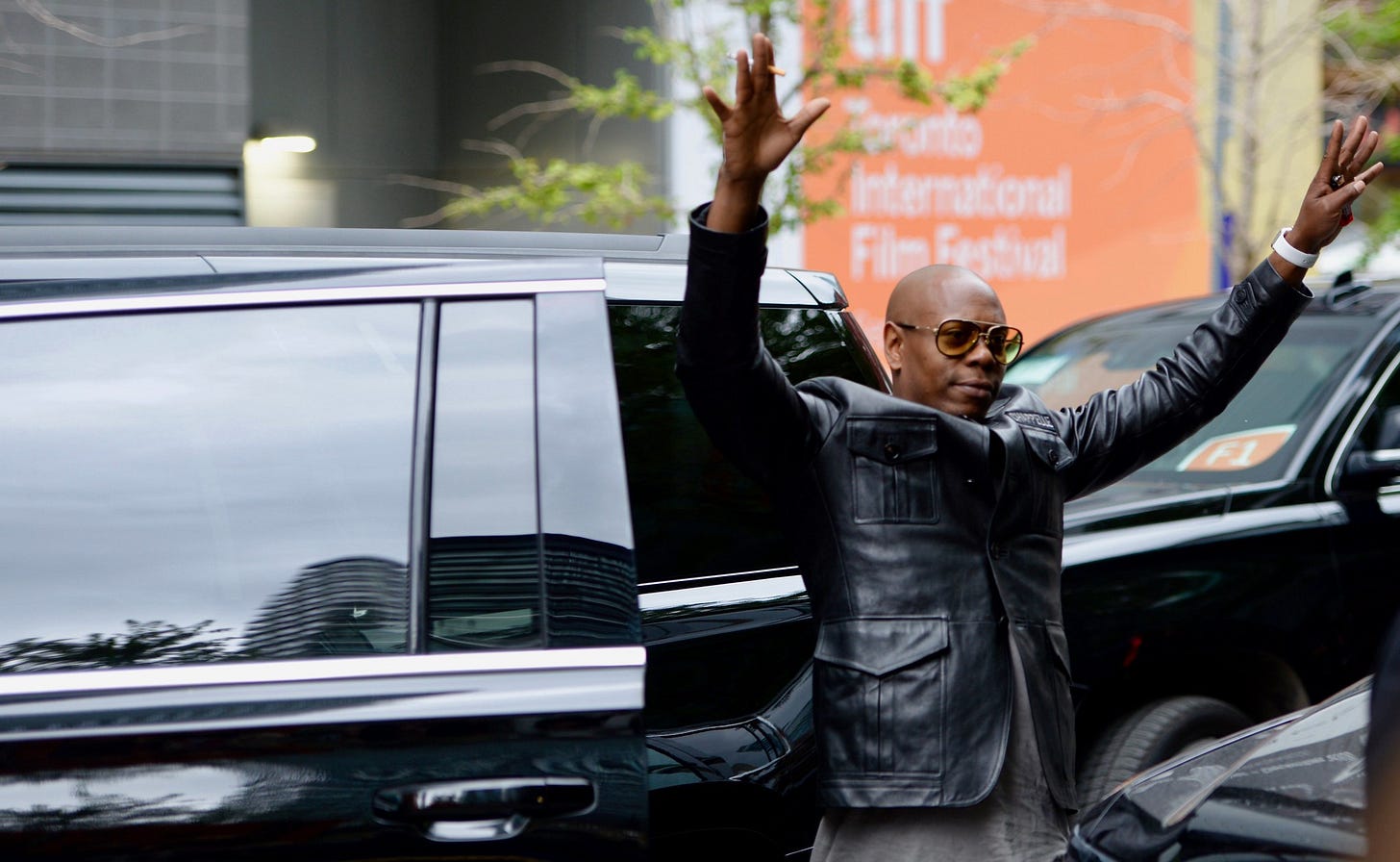 Dave Chappelle holding up his arms in greeting outside a limo Dave Chappelle holding up his arms in greeting outside a limo