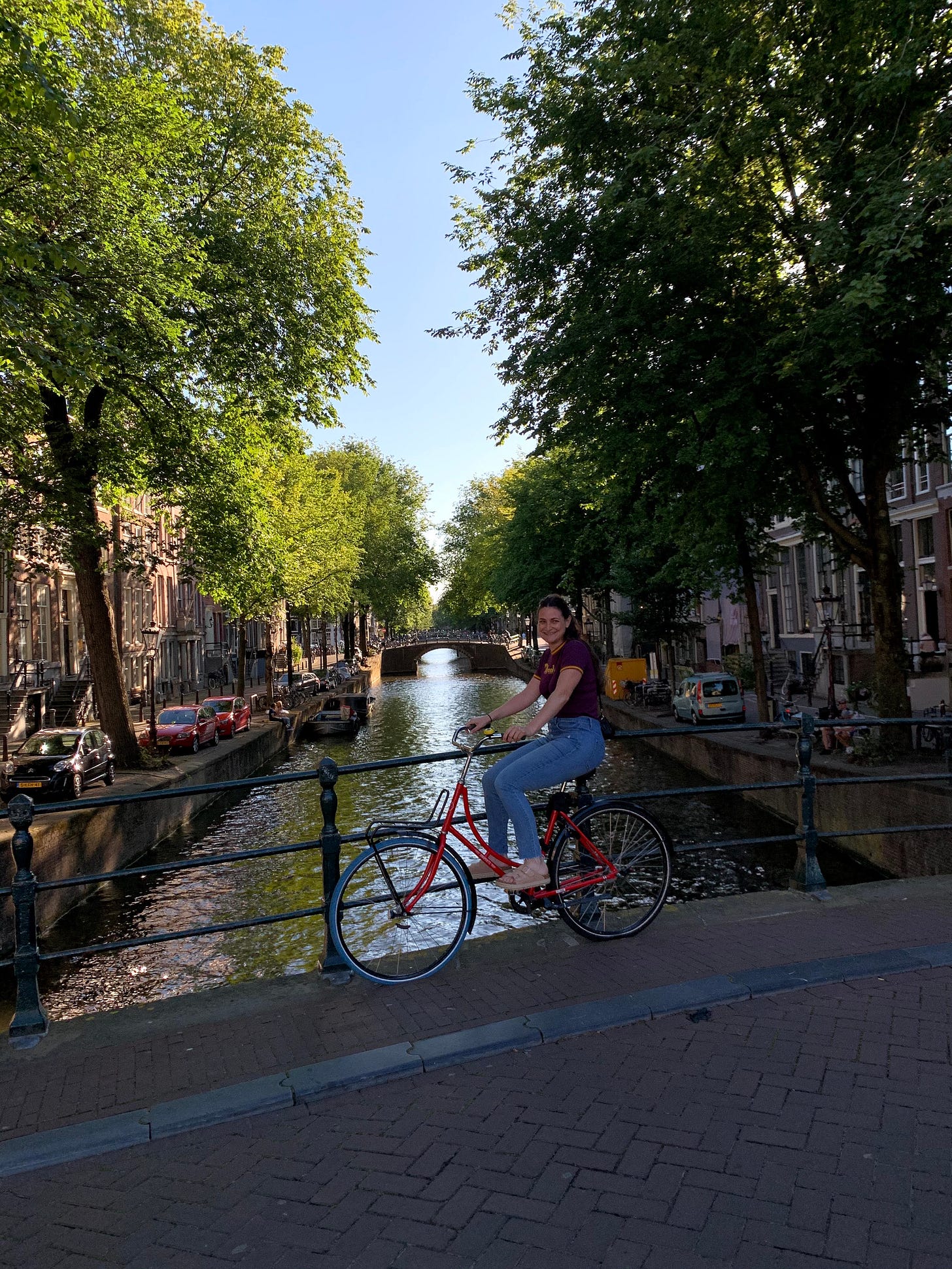A smiling girl on her bike stopped on a bridge in Amsterdam.