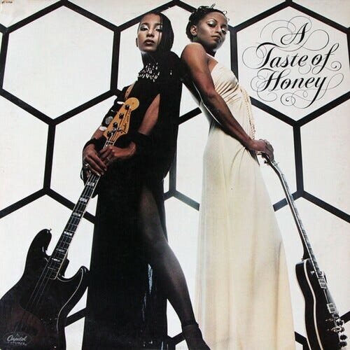 cover of Taste of Honey's debut album; two Black woman in slinky dresses look down at the viewer, resting their hands on cool guitars. cover of Taste of Honey's debut album; two Black woman in slinky dresses look down at the viewer, resting their hands on cool guitars.
