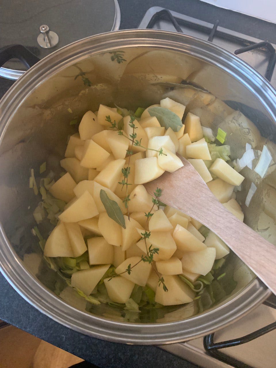 A pot of diced potatoes, sliced leeks, thyme and bay leafs, pre-blend